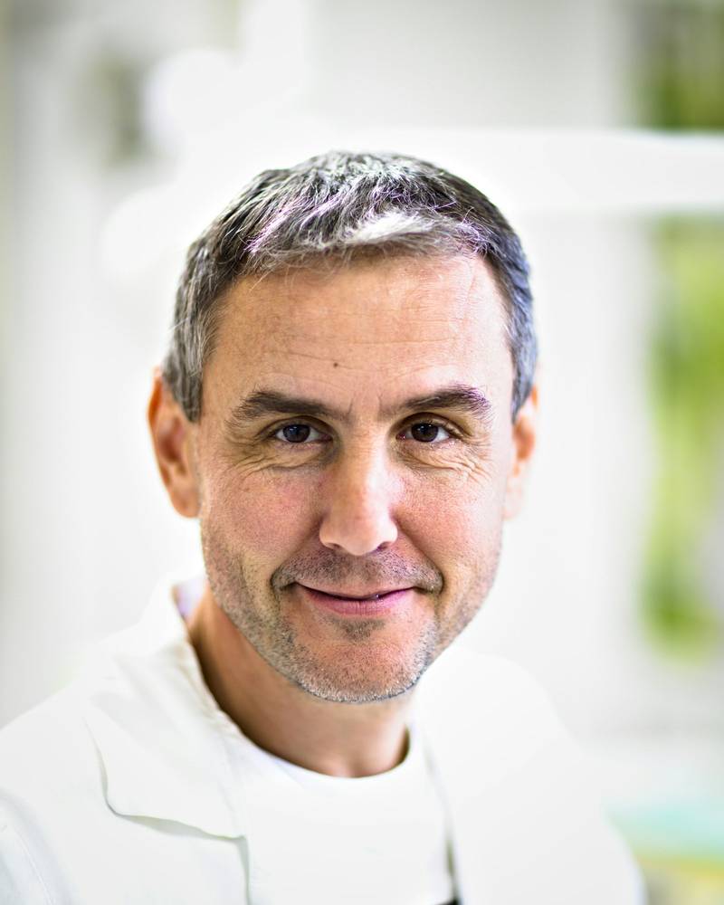 Retrato del Dr. Andrés Navarro, hombre de pelo canoso y barba corta, sonriendo con bata blanca.