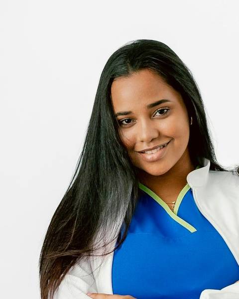 Retrato de la Dra. Marta Ibáñez, mujer joven de pelo largo y liso, sonriendo con pijama sanitario azul y bata blanca.