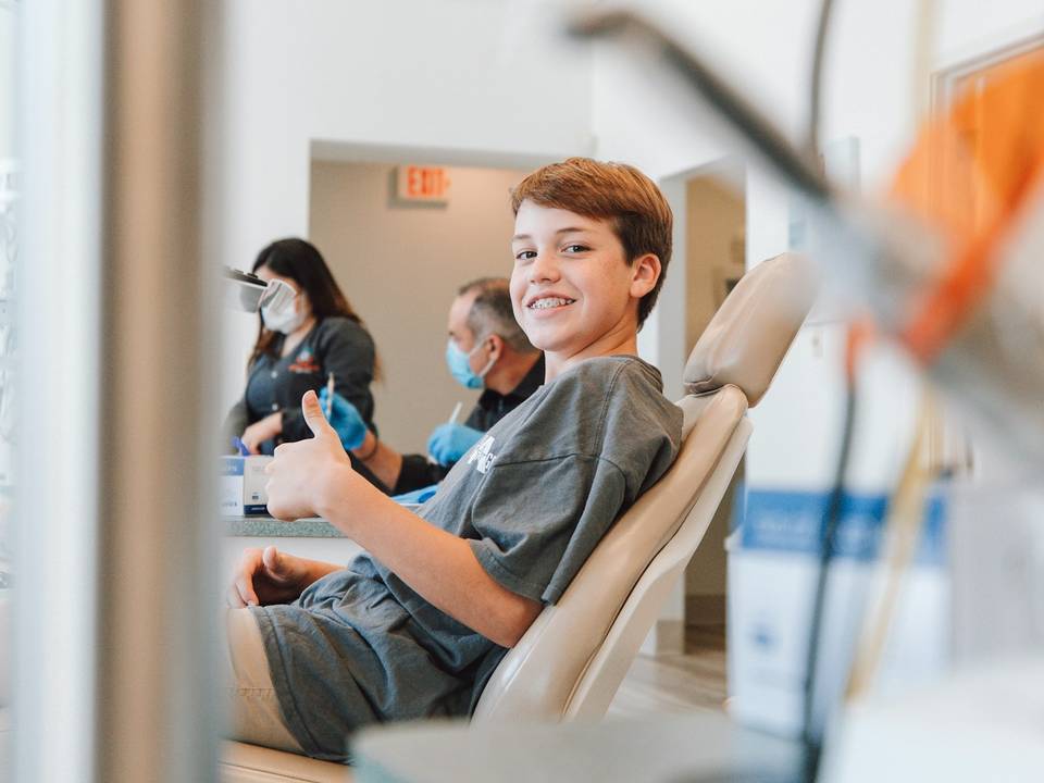 Un niño sonríe sentado en el sillón dental de una consulta luminosa.
